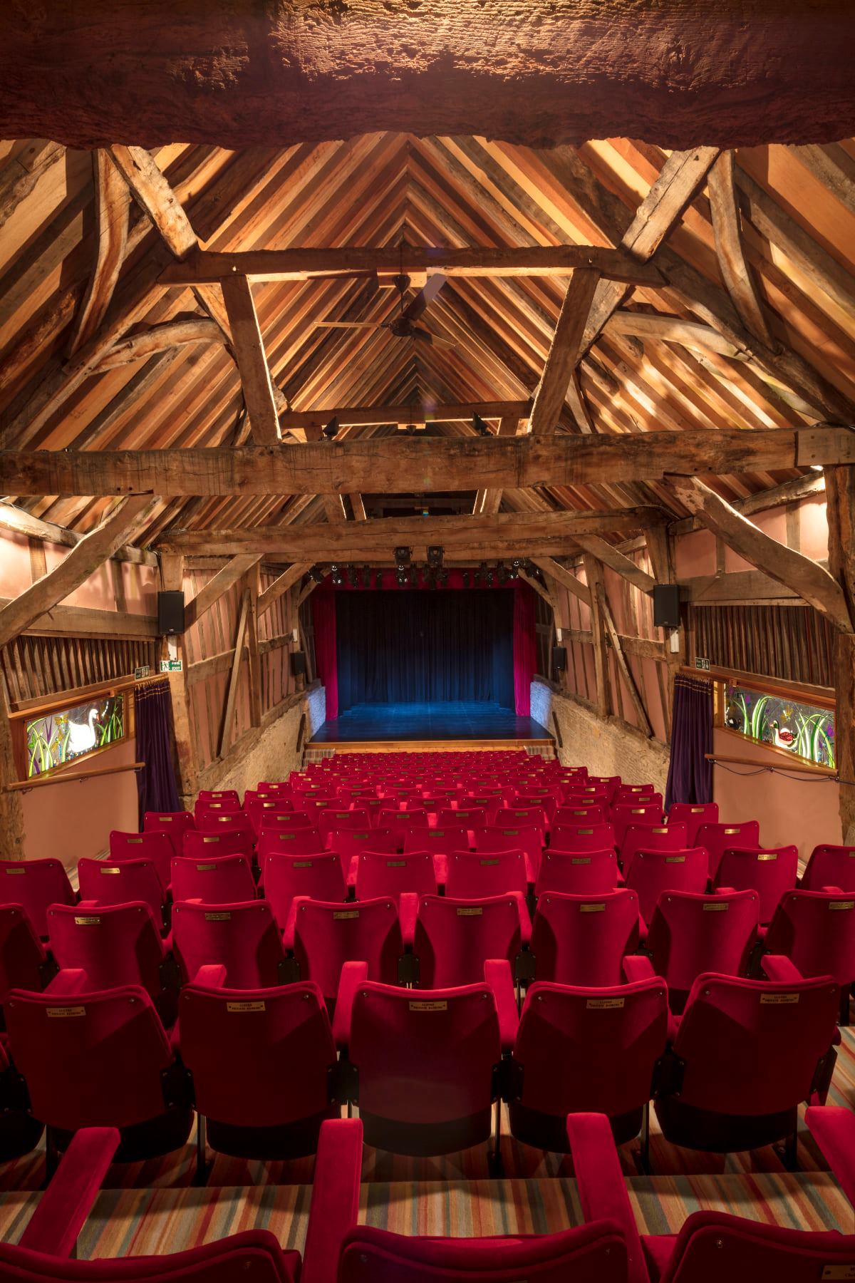 A photo of theatre seats looking towards the stage inside the medieval barn of Bretforton Theatrebarn