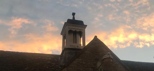 A photo of the bell tower of Bretforton Village School taken as the sun is setting